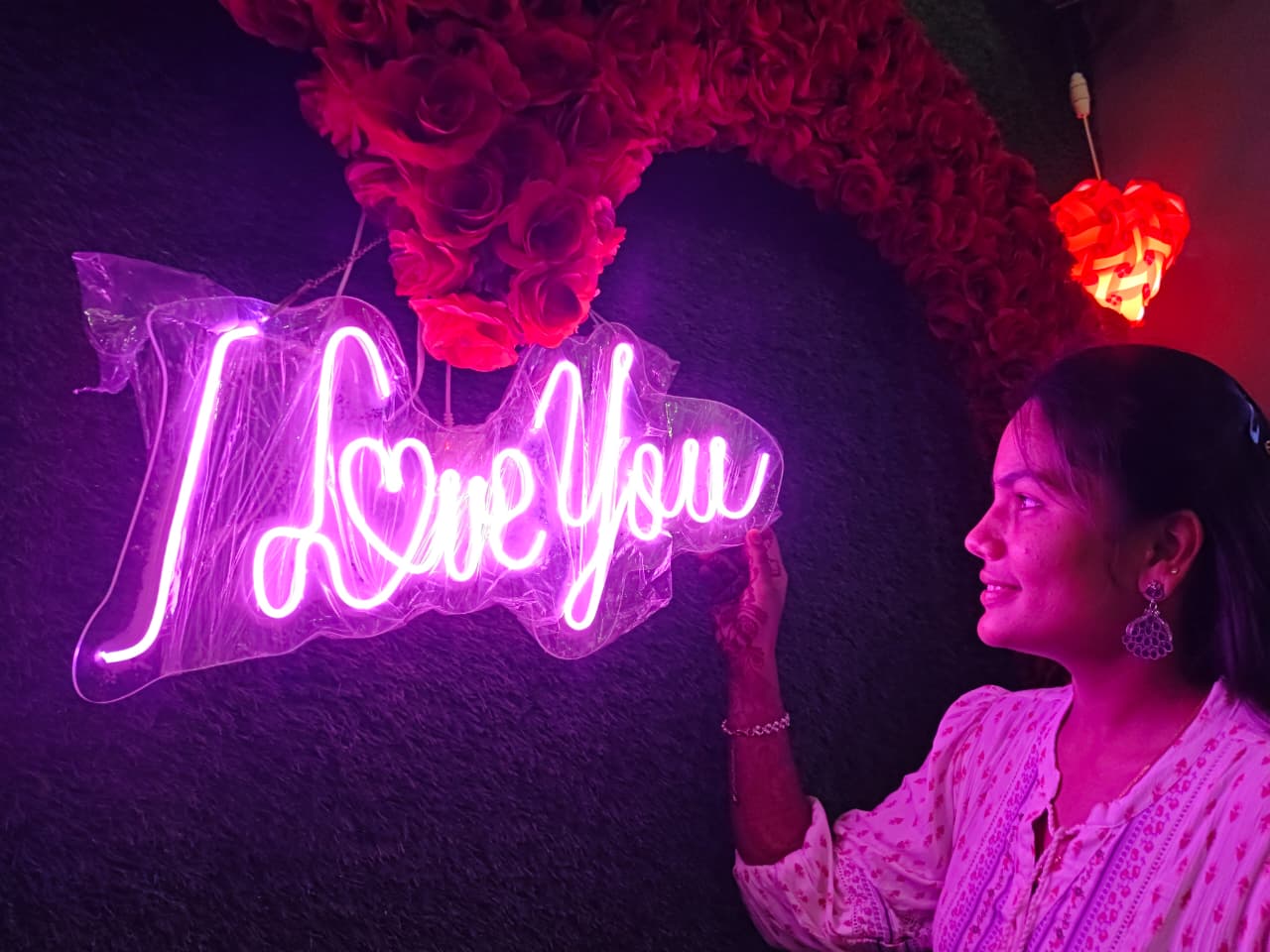 Sravani beside an I Love You neon sign